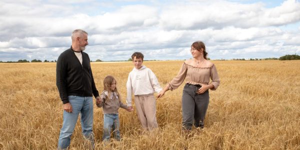 Happy family walking hand in hand through a golden wheat field on a sunny day.